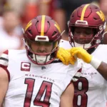 Washington quarterback Sam Howell gets a shoulderpad adjustment from teammate Brian Robinson during the game against the Arizona Cardinals on Sunday at FedEx Field. The Commanders held off the Cardinals, 20-16. (Photo courtesy of SCOTT TAETSCH – GETTY IMAGES)