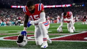 New England Patriots running back Ezekiel Elliott kneels in prayer before a recent game. Elliott's former team, the Dallas Cowboys, plan to honor him before Sunday's game at AT&T Stadium in Arlington. (Photo courtesy of CBSSPORTS.COM)