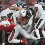 The Philadelphia Eagles shove Jalen Hurts forward on a short-yardage situation against Tampa Bay. The play, sometimes called the "Tush Push," or the "Brotherly Shove," is picking up steam; other offenses are beginning to duplicate it. The New York Jets will likely have to try to stop it this Sunday when they face the Eagles. (Photo by MIKE CARLSON, courtesy of GETTY IMAGES)