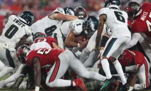 The Philadelphia Eagles shove Jalen Hurts forward on a short-yardage situation against Tampa Bay. The play, sometimes called the "Tush Push," or the "Brotherly Shove," is picking up steam; other offenses are beginning to duplicate it. The New York Jets will likely have to try to stop it this Sunday when they face the Eagles. (Photo by MIKE CARLSON, courtesy of GETTY IMAGES)