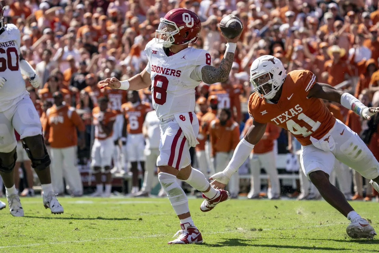 Oklahoma quarterback Dillon Gabriel (left) avoids the rush of Texas linebacker Jaylan Ford. OU scored late to top the Longhorns, 34-30. (Photo by JEFFREY McWHORTER - COURTESY OF THE ASSOCIATED PRESS)