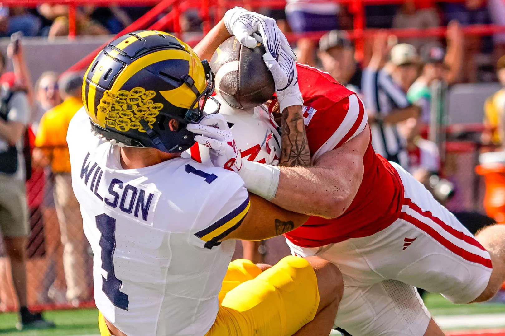 Michigan receiver Roman Wilson (1, left) hauls in a pass for a touchdown, using the helmet and back of Nebraska receiver Isaac Gifford for help. (Photo by DYLAN WIDGER, courtesy of USA TODAY)