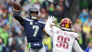 Seattle quarterback Geno Smith (left) avoids pass rush. Smith and the Seahawks (6-3) will play at the L.A. Rams (3-6) today. (Photo courtesy of SPORTS.MYNORTHWEST.COM)