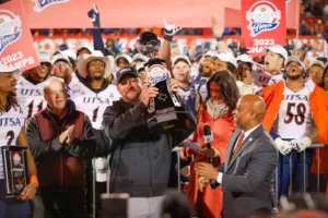 University of Texas-San Antonio coach Jeff Traylor (center) hoists the Scooter's Coffee Frisco Bowl trophy after beating Marshall last week in that bowl game. Traylor is a rising star in the college football world. (Photo courtesy of FOR THE WIN)