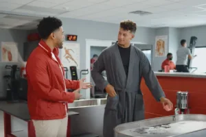 Kansas City Chiefs quarterback Patrick Mahomes (right) talks with "Jake From State Farm" in a commercial. The Chiefs lost at home to the Las Vegas Raiders on Christmas Day, dropping their overall record to 9-6. Kansas City is still likely to win the AFC West, but the Chiefs seem distracted, and Outkick.com writer Armando Salguero has nailed it in an editorial on outkick.com on Tuesday. (Photo courtesy of CHICAGOBUSINESS.COM)