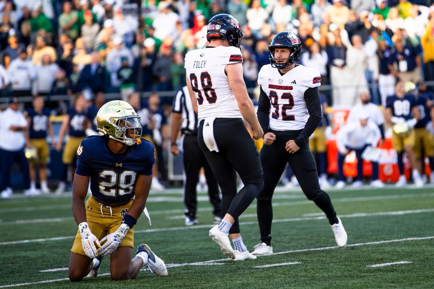 Notre Dame's Christian Gray (29) kneels as Northern Illinois kicker Kanon Woodill (92) hits the go-ahead field goal Saturday, giving NIU a 16-14 lead, then celebrates with holder Tom Foley. NIU would beat Notre Dame by that score. (Photo by MICHAEL CATERINA, courtesy of THE ASSOCIATED PRESS)